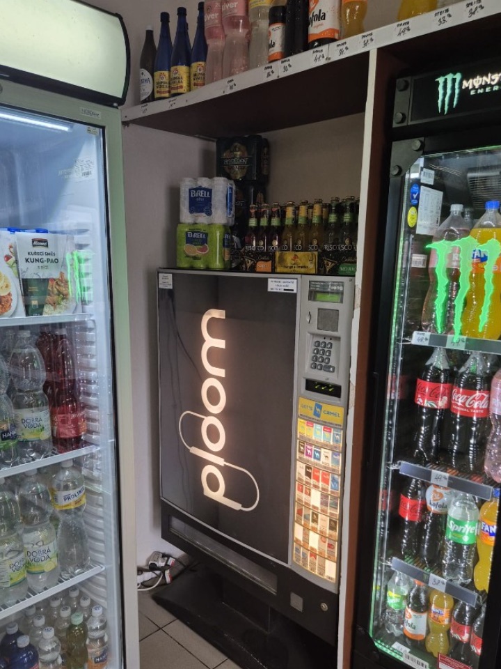Cigaretový automat ve večerce mezi chladicími vitrínami